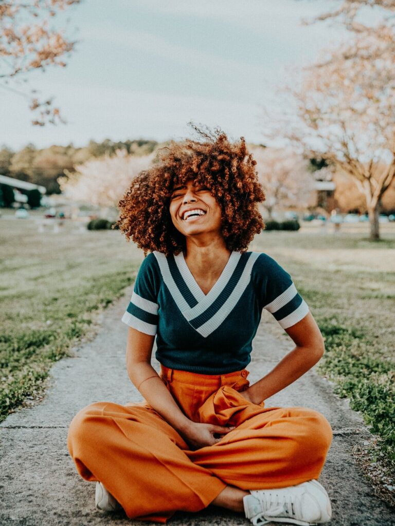 Women laughing sitting cross legged on the sidewalk